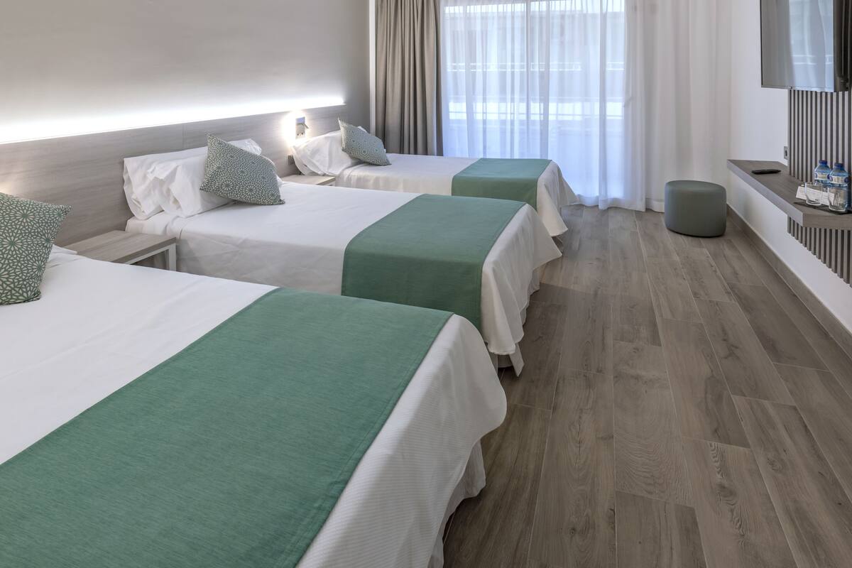 Habitación de hotel con dos camas, televisión y una pequeña zona de estar.