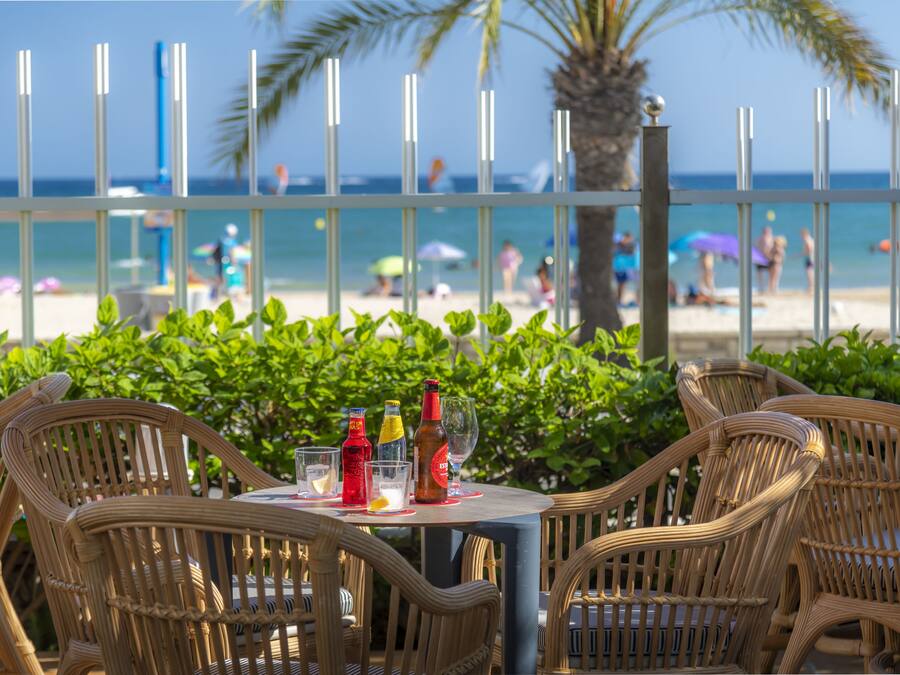 Un tavolo con sedie in vimini e vista sulla spiaggia.