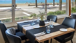 Ein Essbereich mit Blick auf den Strand, ausgestattet mit Tisch, Tellern, Gläsern und Besteck.