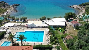 Un resort con piscina, sombrillas de playa y vistas al mar.