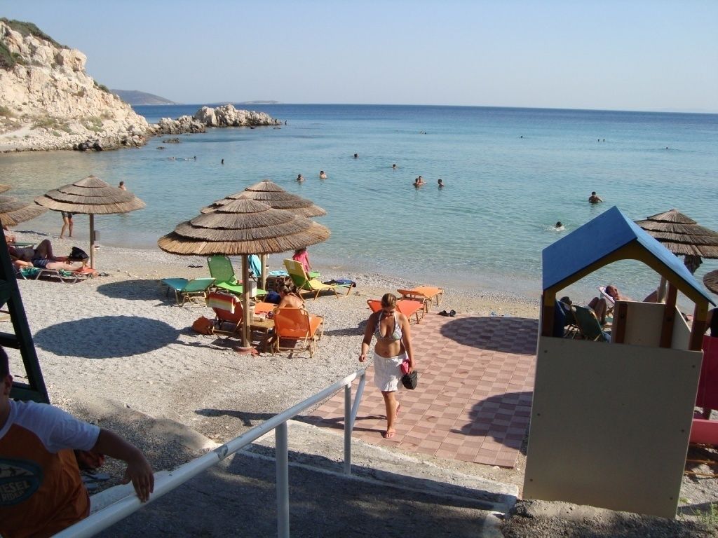Une plage avec des parasols, des chaises longues et un poste de surveillance pour les sauveteurs.