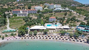 Un complejo turístico en la costa con varias edificaciones, una playa y una piscina.