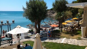 Un área junto a la playa con sombrillas, sillas de descanso y una piscina.