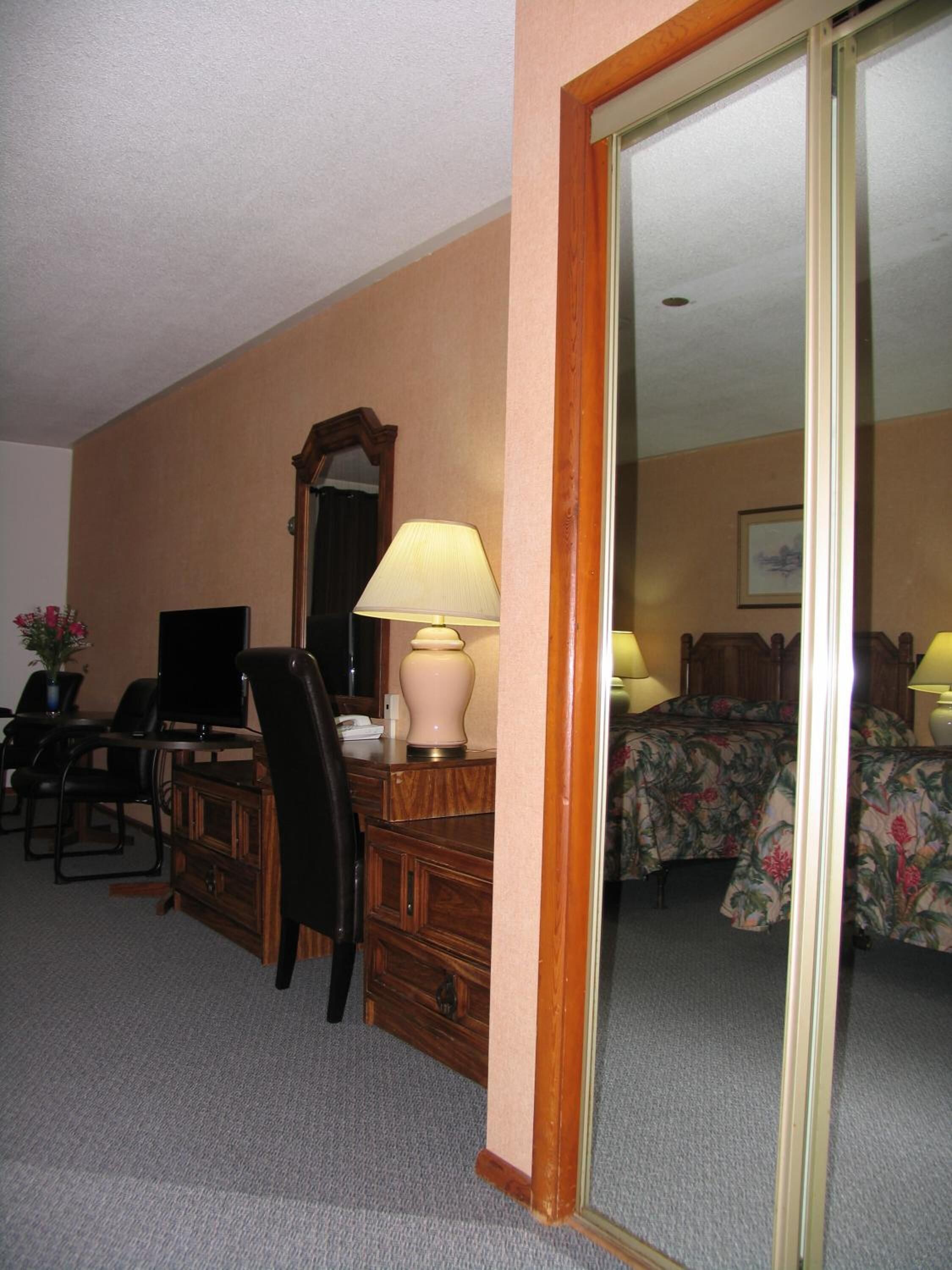 A hotel room with a desk, chair, television, and a bed with floral bedding.