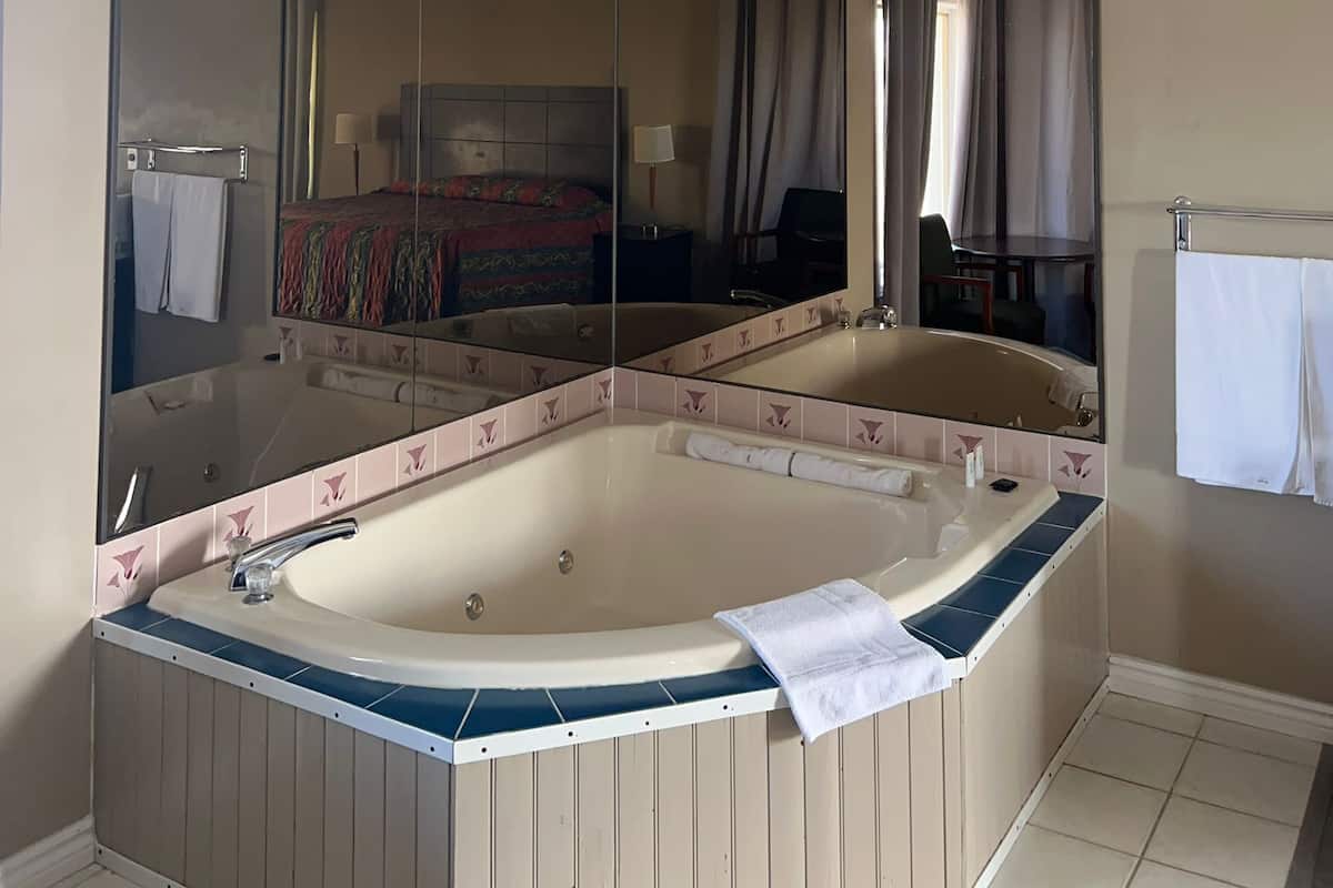 Un baño moderno con una bañera independiente, un espejo grande y una lámpara en el techo.