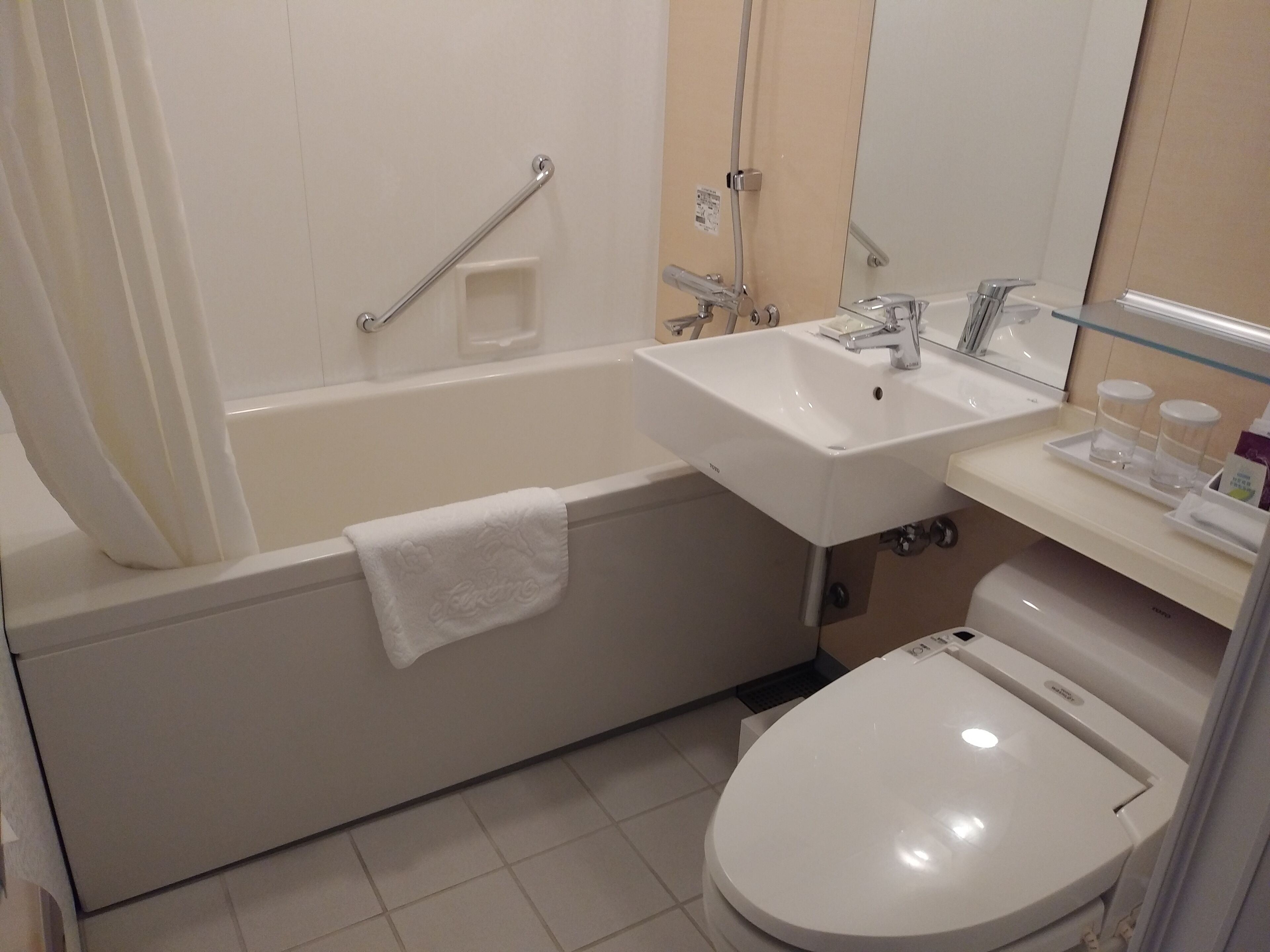 Un baño con bañera, lavamanos, inodoro y espejo.
