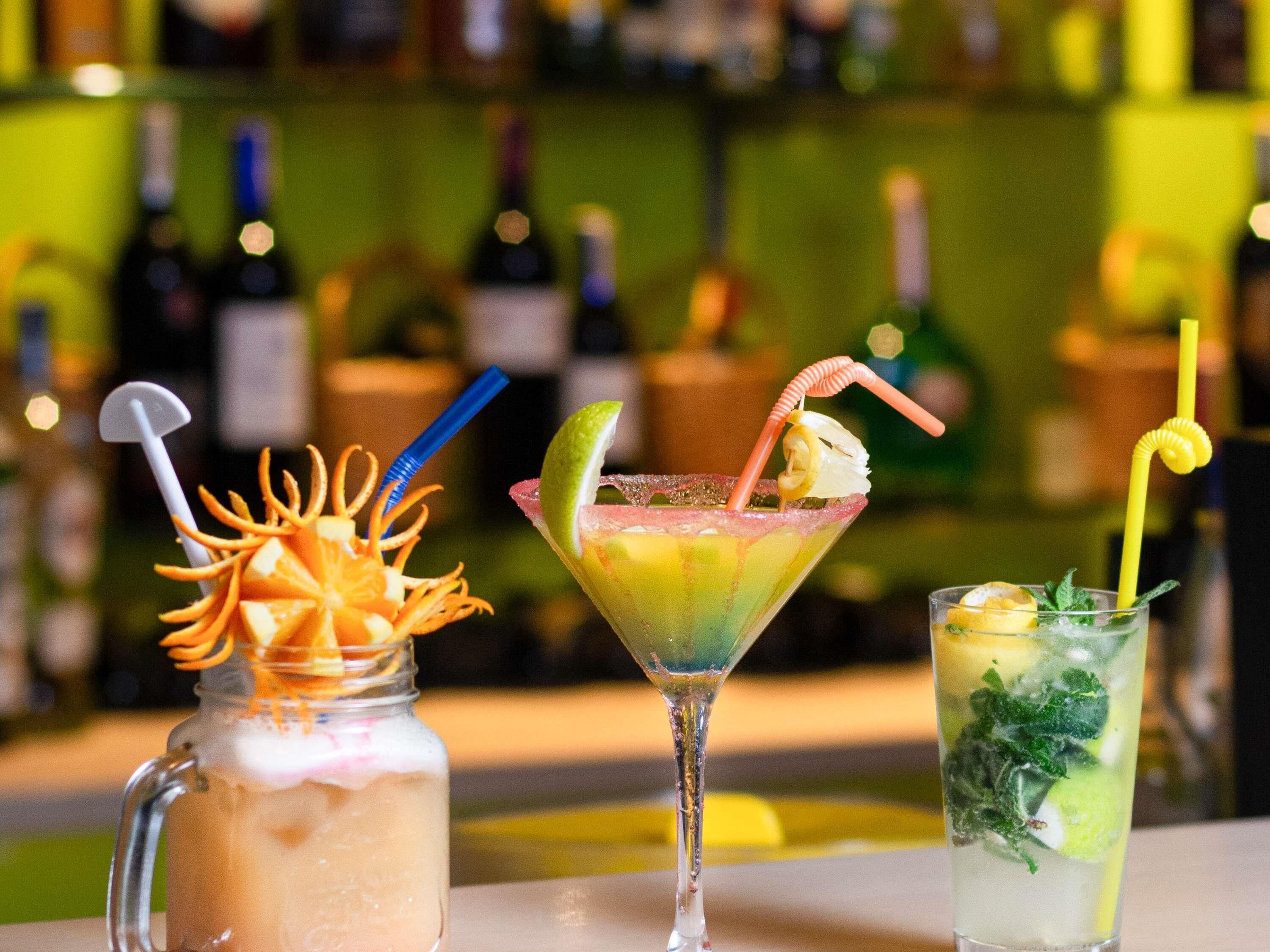 Trois verres posés sur le comptoir d’un bar, avec des bouteilles en arrière-plan.