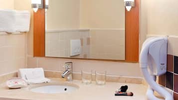 Une salle de bain équipée d’un lavabo, d’un miroir, d’un porte-serviettes et d’un sèche-cheveux.