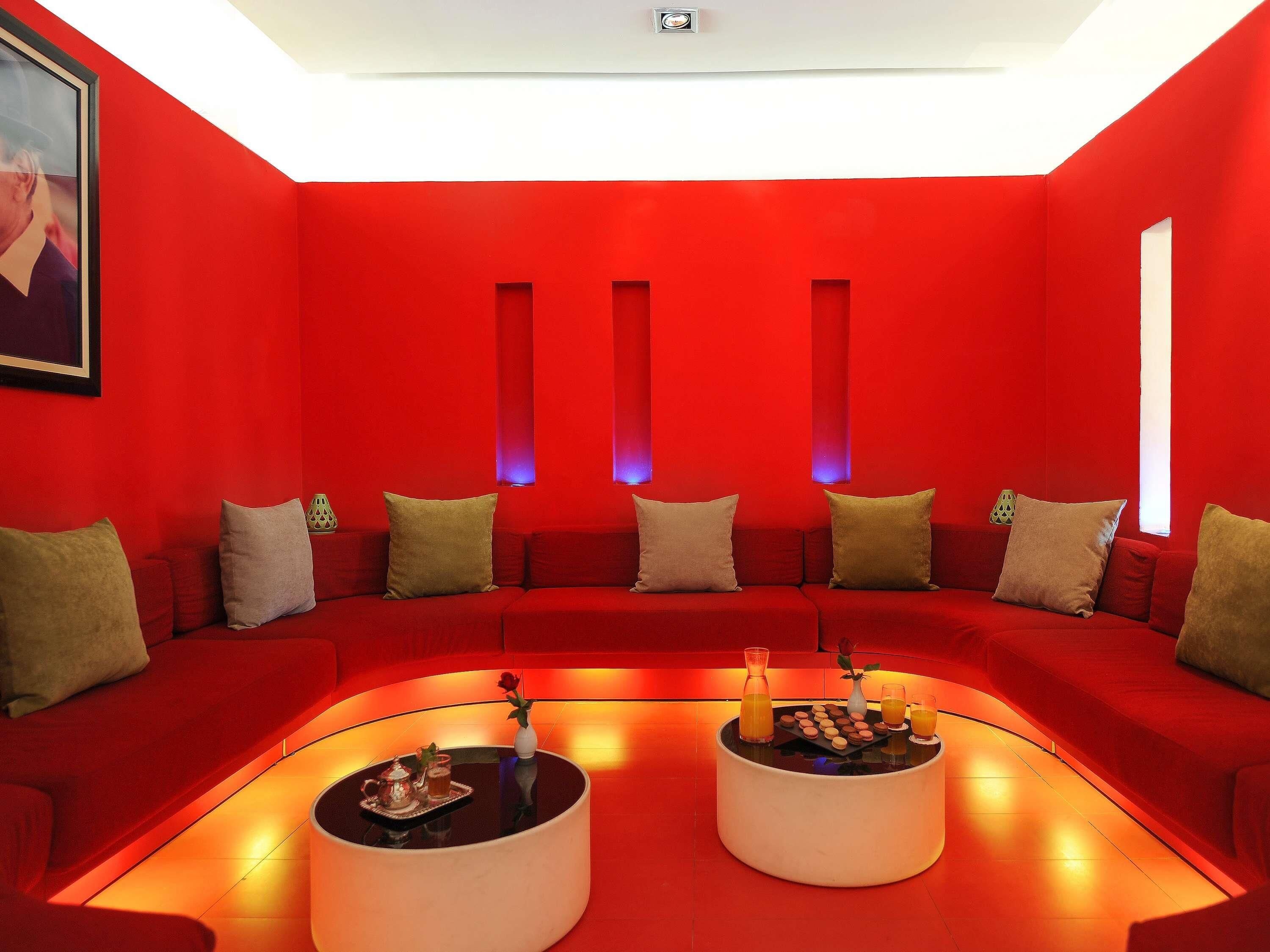 A red-themed living room with a sofa, two coffee tables, and a painting on the wall.