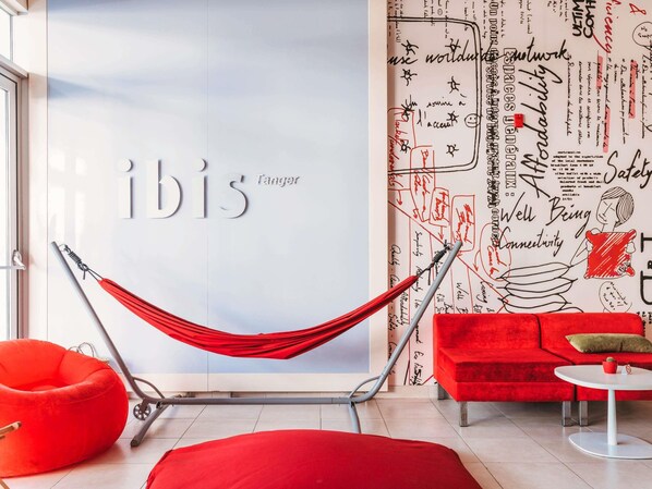 A hammock chair in a modern room with a red couch and a white table. - ibis Tanger City Center (Tangier)