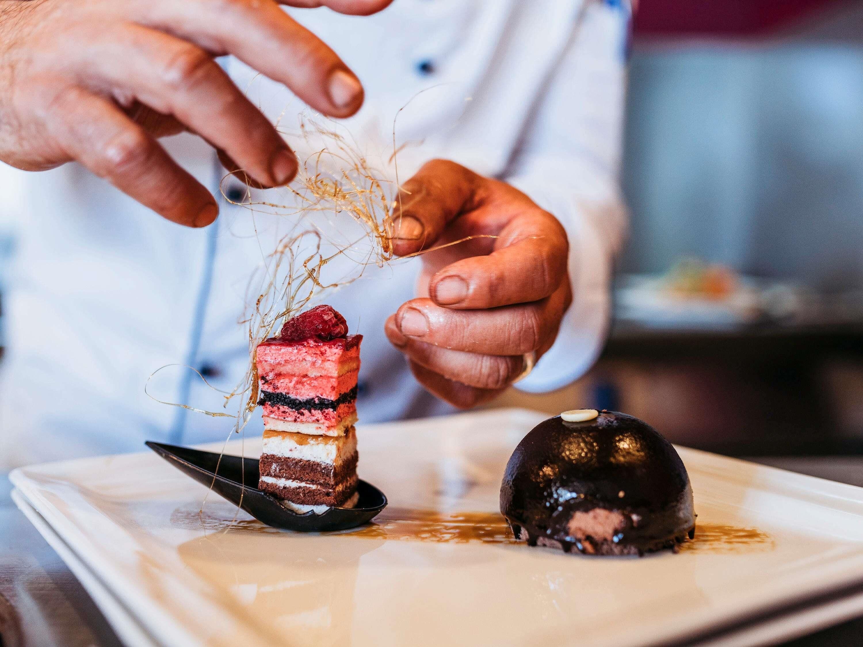 Un postre con capas de pastel y una esfera de chocolate sobre un plato blanco.