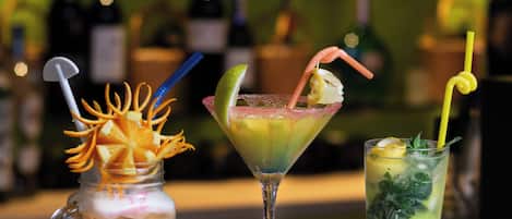 Tres bebidas sobre una barra, con un fondo borroso de botellas.