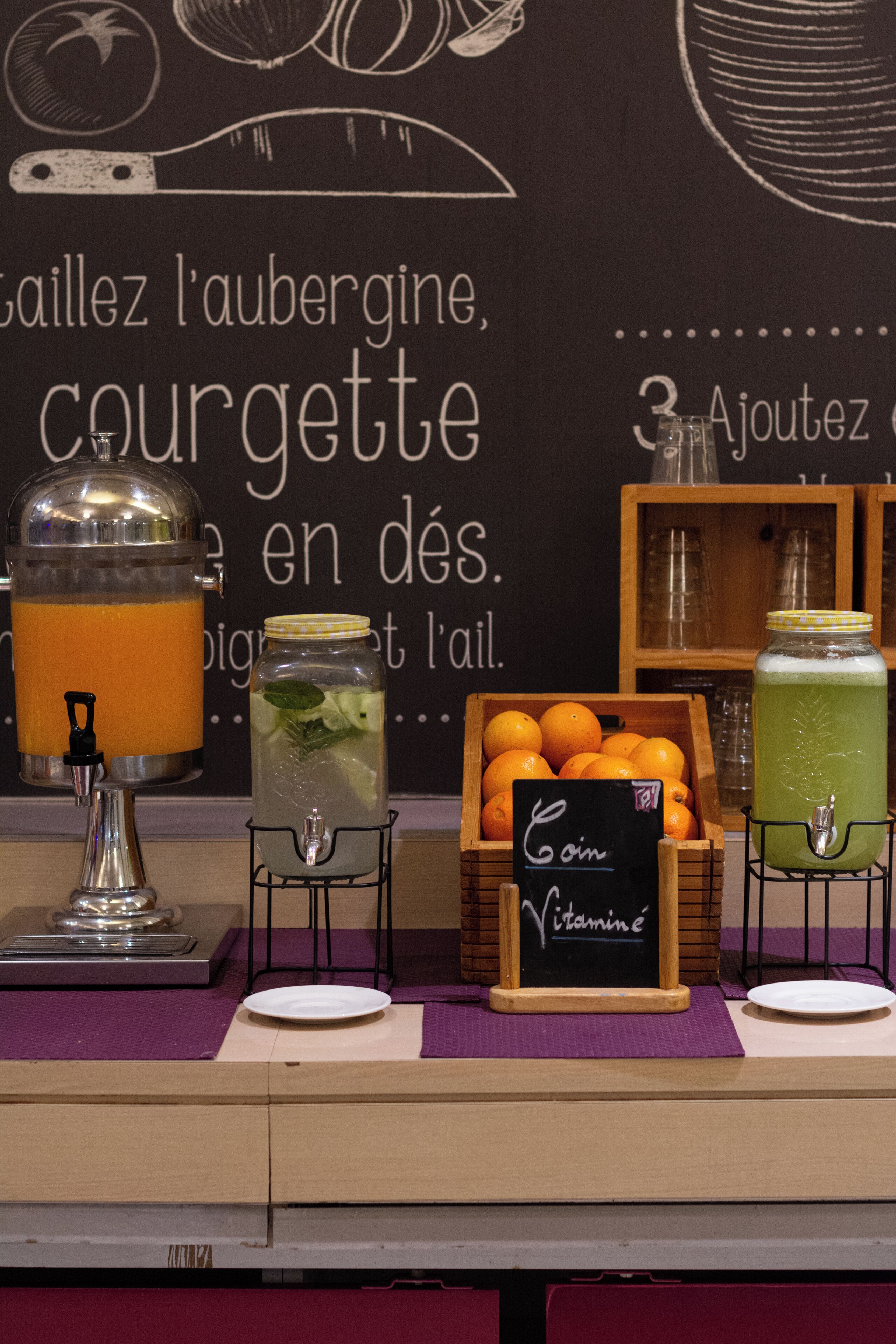 Un bar à jus proposant une variété de boissons et où l’on peut voir des oranges fraîches exposées.
