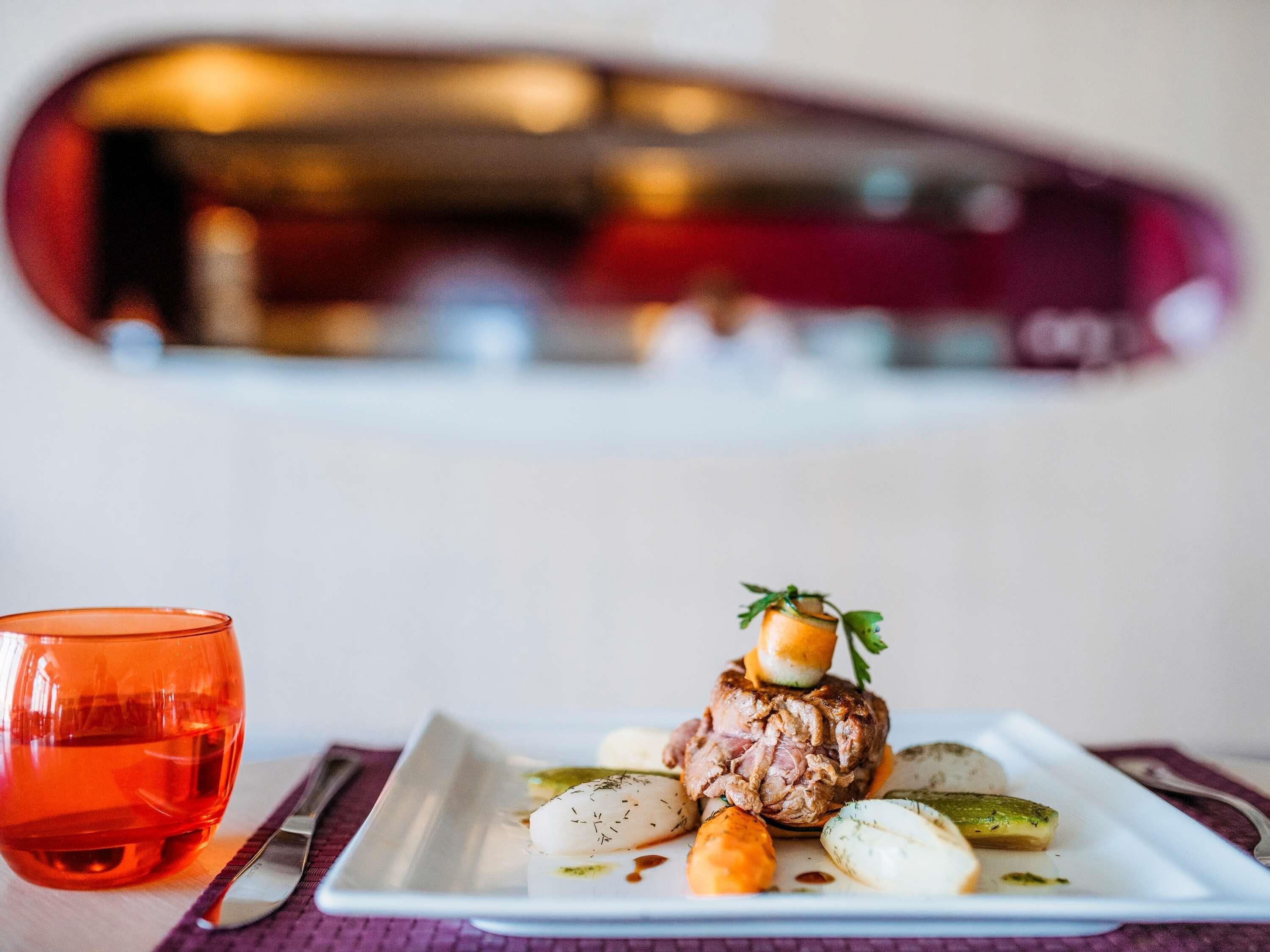A plate of food with a glass of red drink on a table.