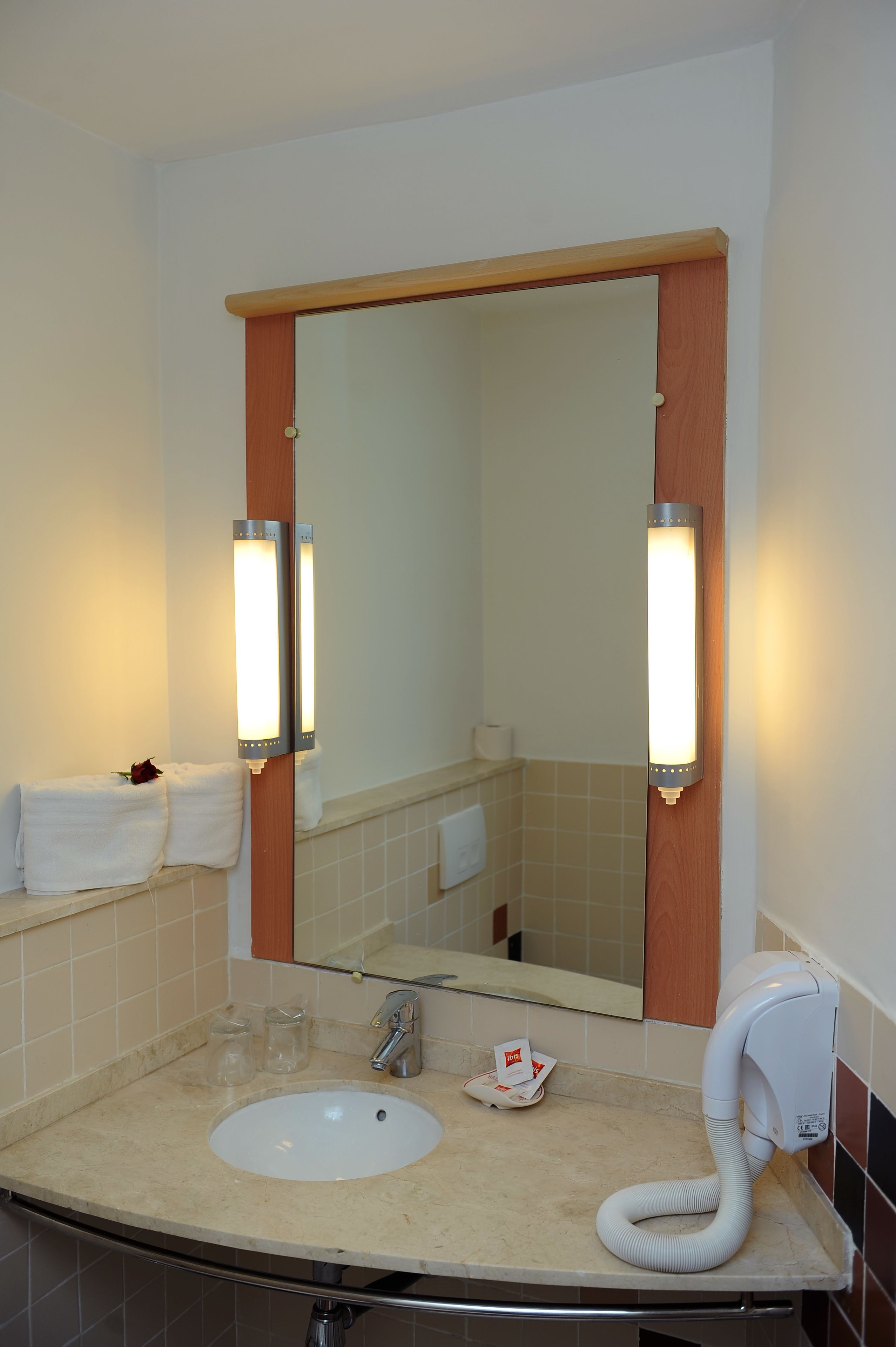 Un bagno con lavandino, specchio, asciugamani e asciugacapelli.