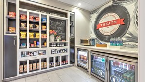 Et område med snacks og drikkevarer, med hylder fulde af snacks, et kridttavleskilt og køledisplay til drikke.