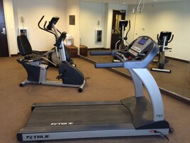 Un gimnasio con equipo de ejercicio variado, incluyendo cintas de correr y bicicletas estáticas.