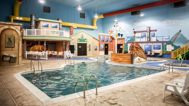 Piscina interna com um mural com tema de navio, restaurante chamado 'Steamboat Alabama' e área de recreação com escorregador.