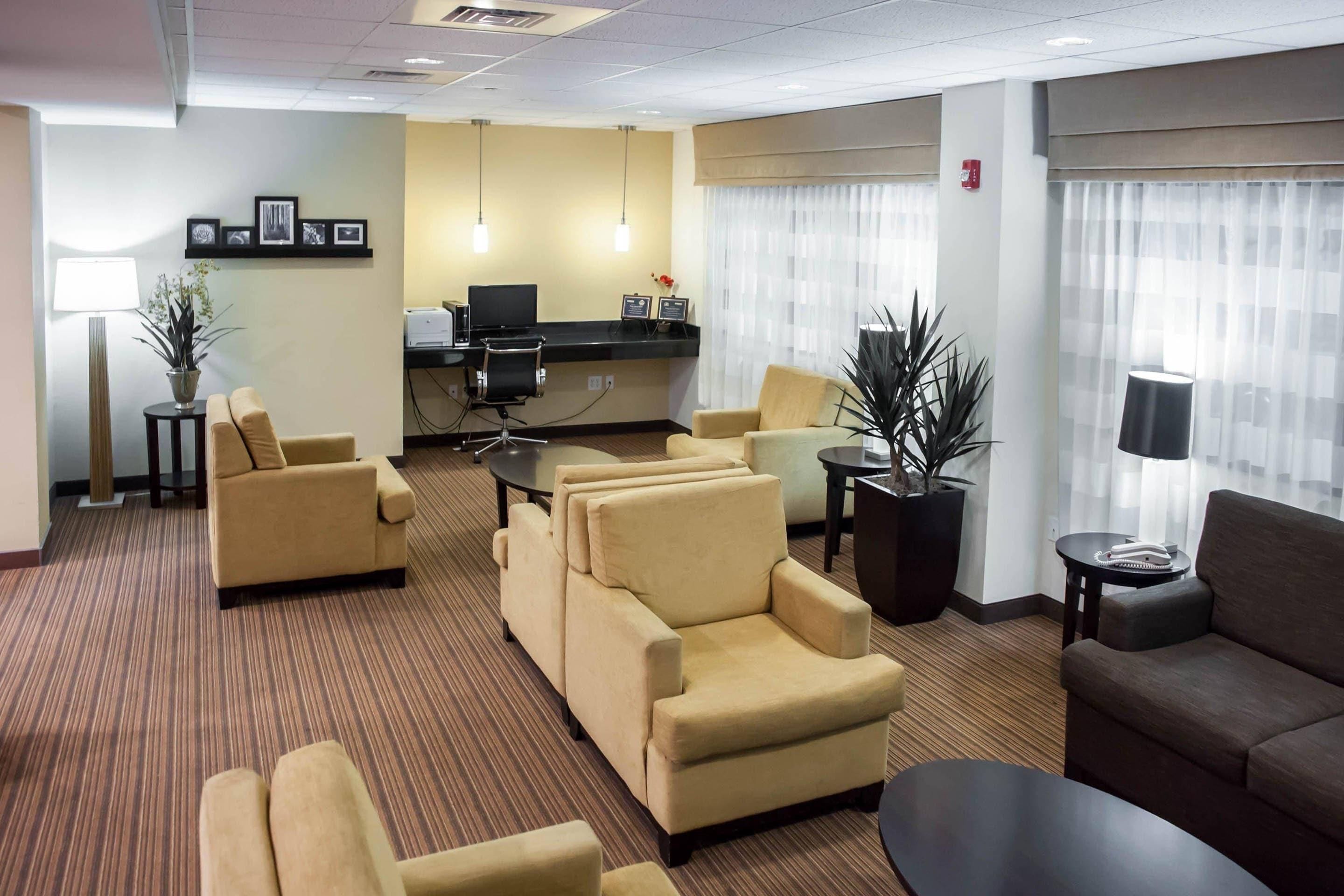A hotel room with a seating area, a desk, and a computer.
