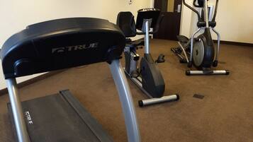 A gym with a treadmill, stationary bike, and elliptical machine.