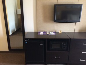 Une chambre d’hôtel équipée d’un bureau, d’un four à micro-ondes, d’une télévision et d’un petit réfrigérateur.