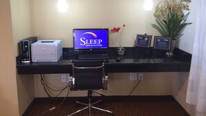 A reception desk with a computer, printer, and a sign for Sleep Inn & Suites.