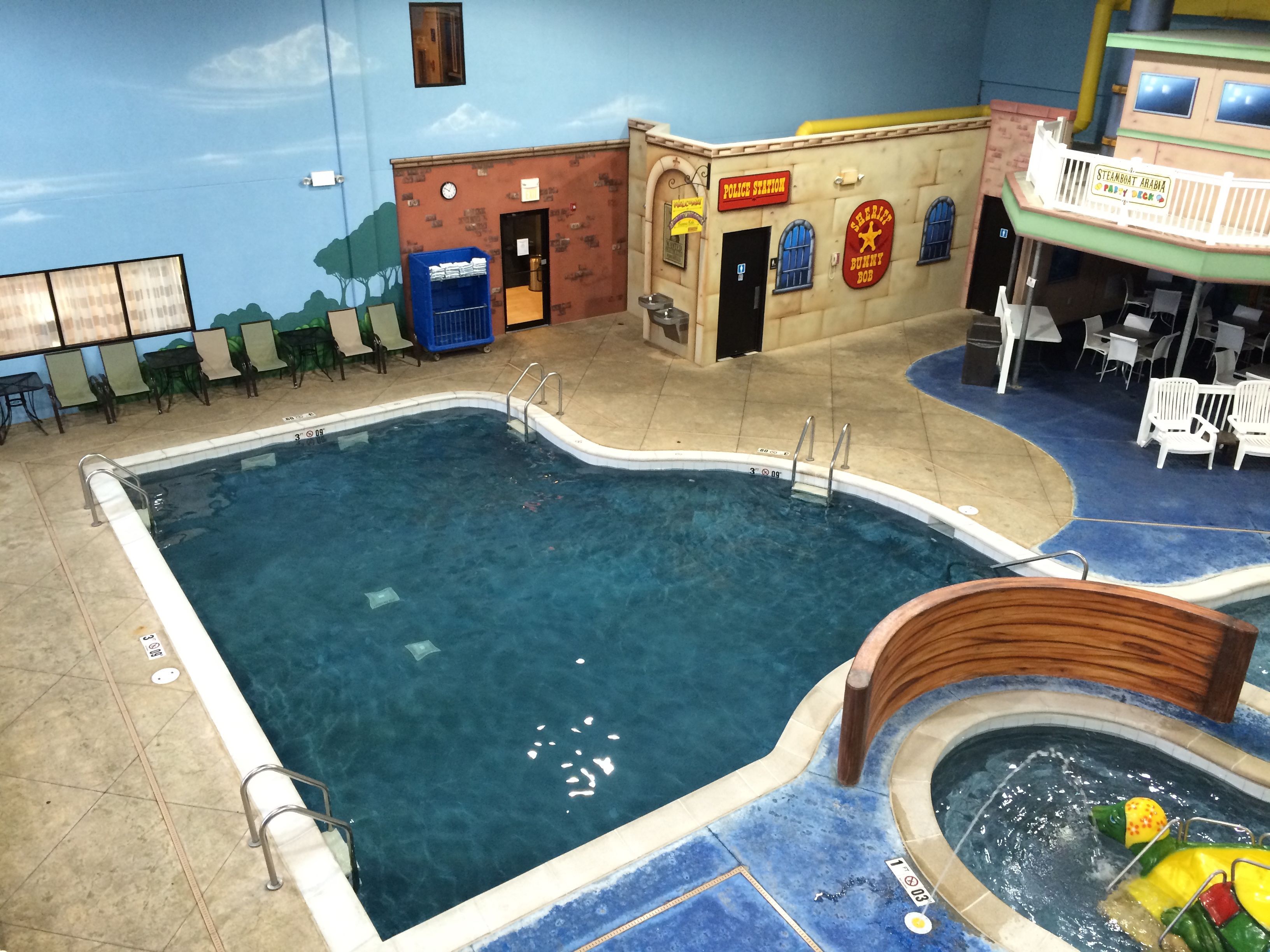 An indoor swimming pool with a lifeguard stand, a play area, and a children's playroom.