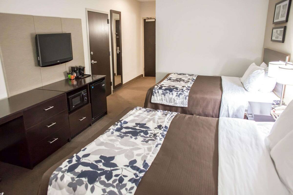 Une chambre d’hôtel avec deux lits, une télévision, un bureau avec une machine à café et une armoire.