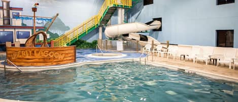 An indoor water park with a wooden boat labeled "LIBERTY LAGOON," a water slide, and a pool area with lounge chairs.