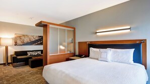 Een hotelkamer met een groot bed, een slaapbank, een bureau en een wandlamp.