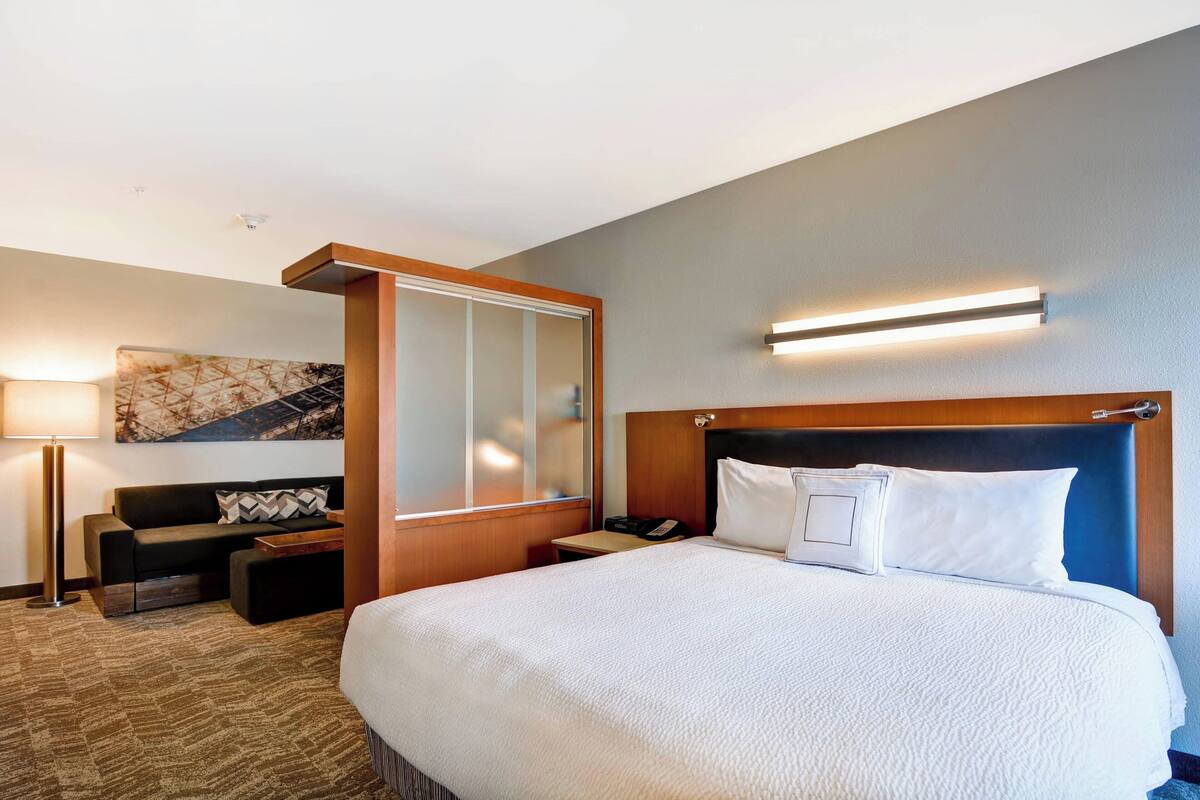 Ein Hotelzimmer mit einem großen Bett, einer Couch, einem Schreibtisch und einer Wandleuchte.