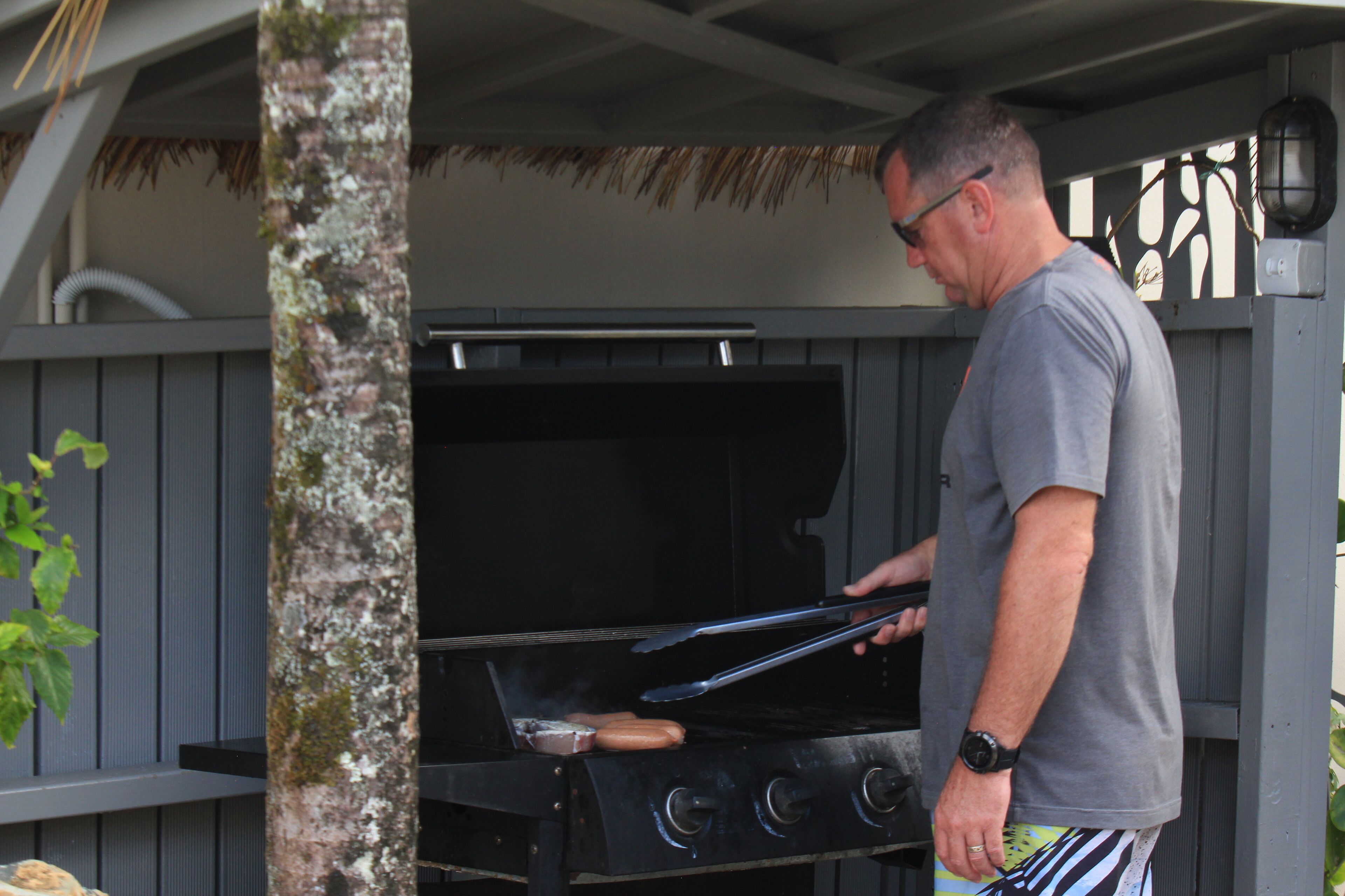 A man grilling sausages on an outdoor barbecue grill.