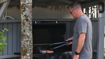 A man grilling sausages on an outdoor barbecue grill.
