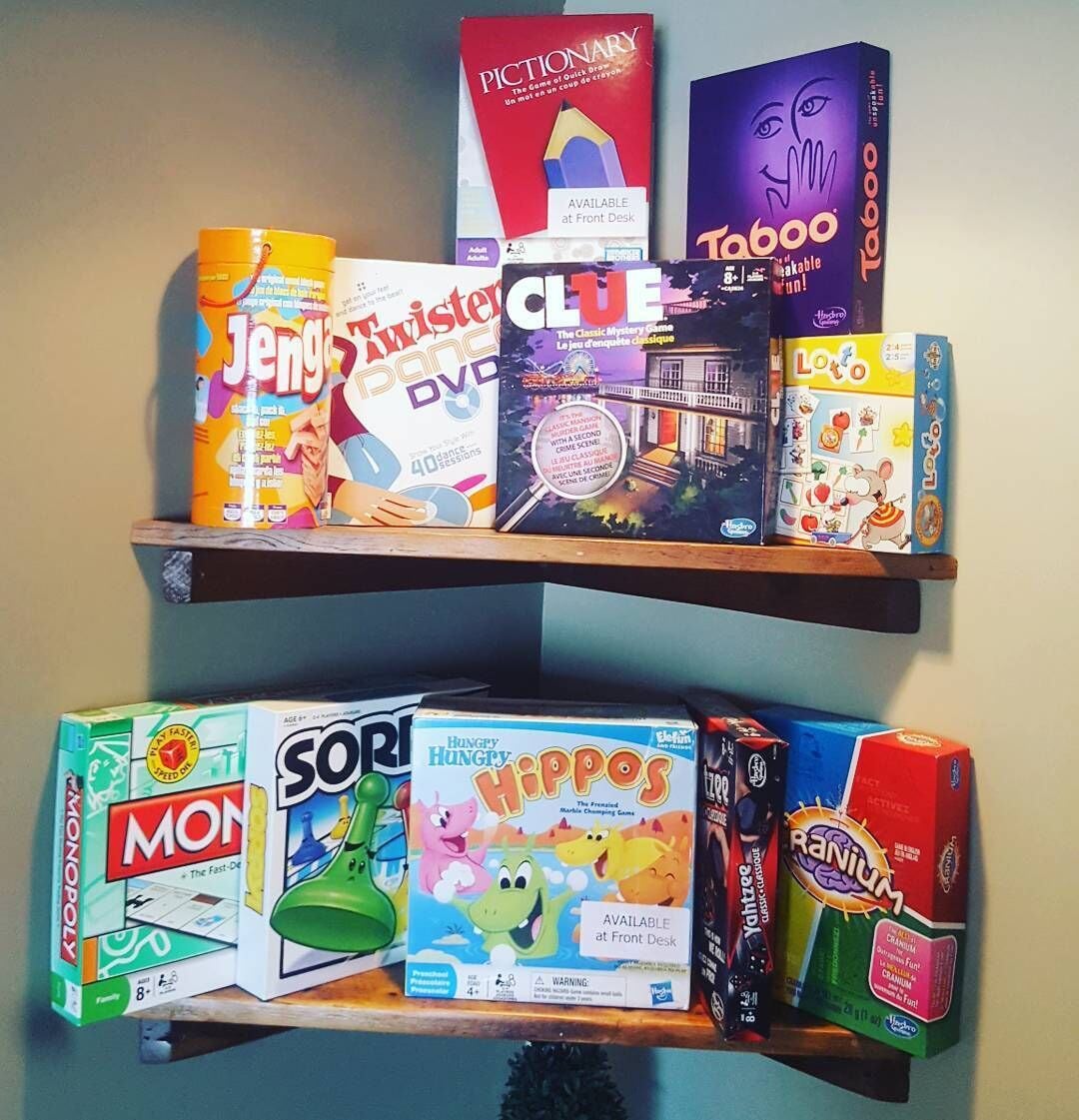 Un estante con diversos juegos de mesa y rompecabezas, incluyendo Monopoly, Twister y Clue.