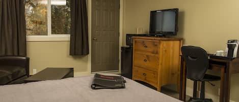 Une chambre d’hôtel comprenant un lit, un bureau, une chaise, une télévision et une commode.