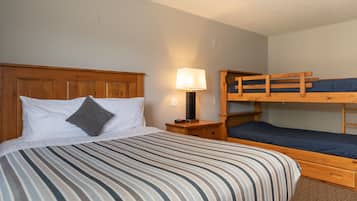 Una habitación con una cama individual, una mesita de noche, una lámpara y una cama litera.