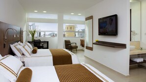 Habitación de hotel con dos camas, un escritorio, una silla, un televisor y un baño con espejo y lavabo.