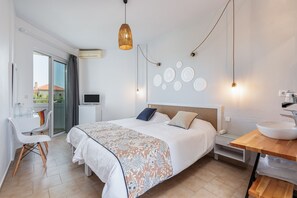 A modern bedroom with a bed, bedside table, and a desk with a chair. - Mrs Chryssana Beach Hotel by GHH (Platanias)