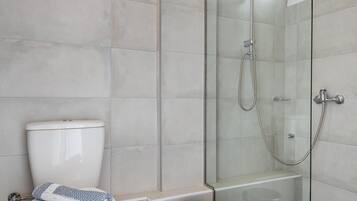 Une salle de bain moderne dotée d’une douche à parois de verre, de toilettes et d’un bidet.