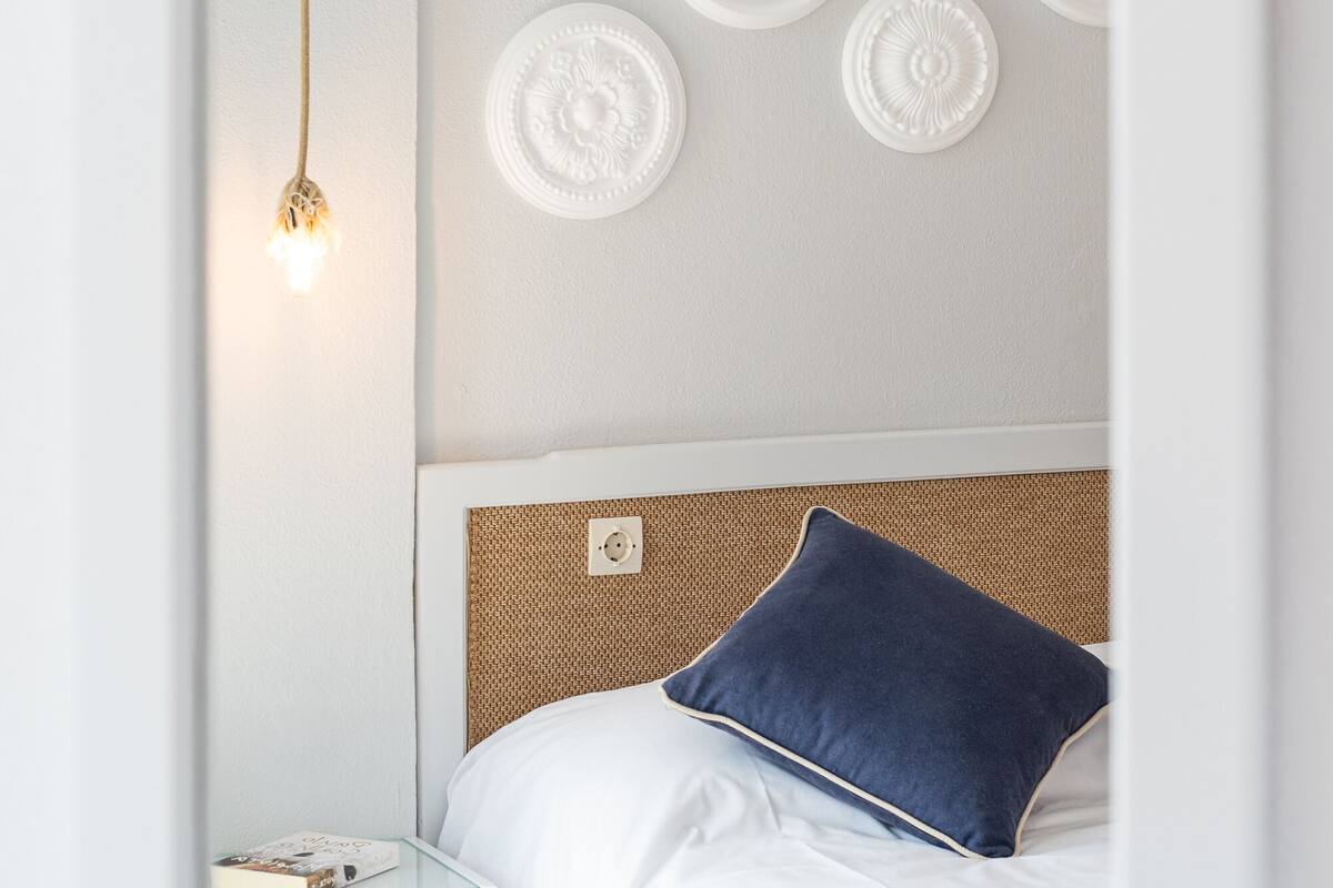 Un dormitorio ordenado con una cama, una mesita de noche y placas decorativas en la pared.