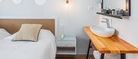 A modern bedroom with a bed, bedside table, and a wooden bench.