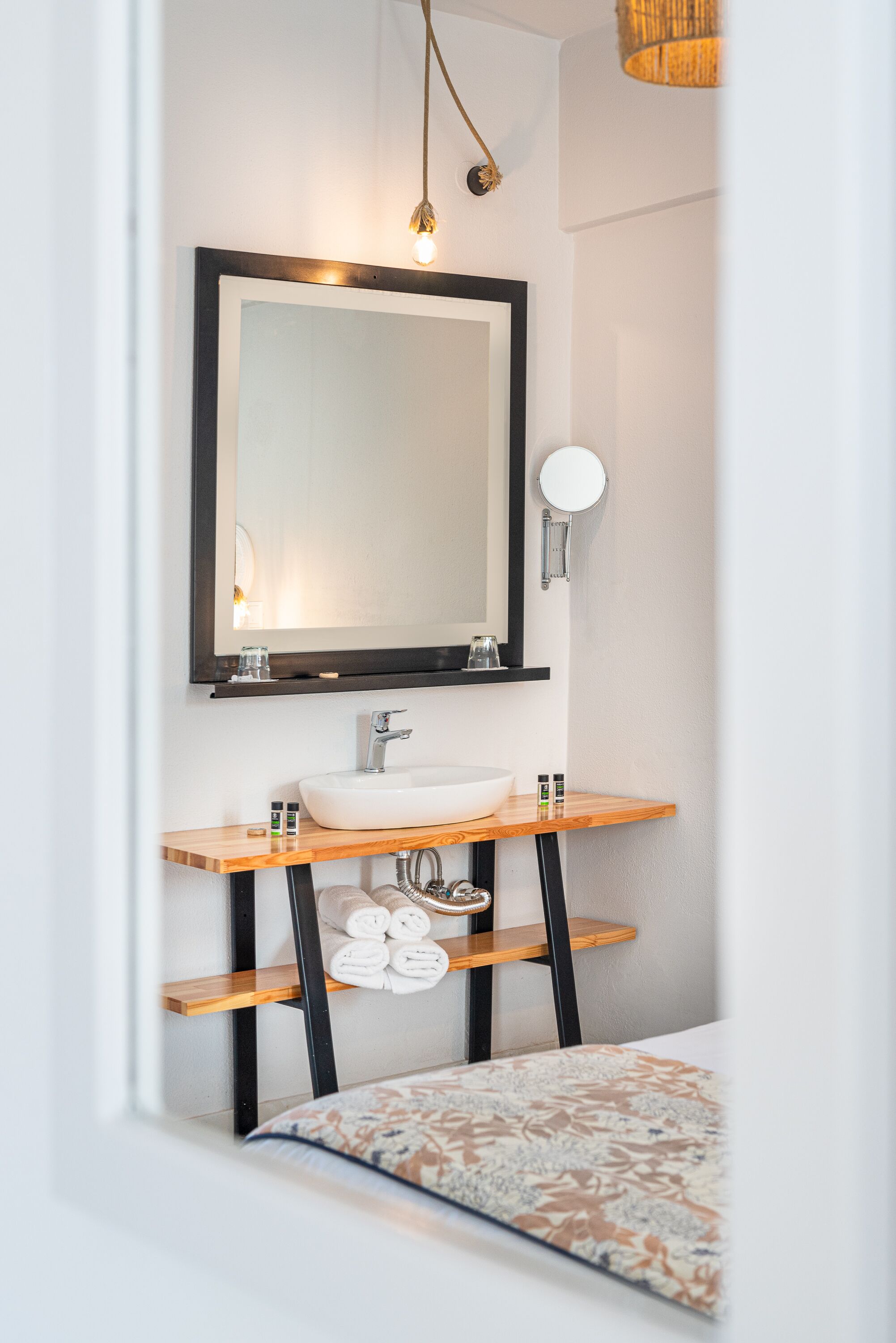 Une salle de bain moderne avec un grand miroir, un lavabo blanc et des étagères en bois.