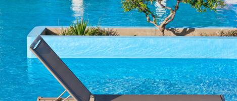 A pool with a lounge chair and a small tree.