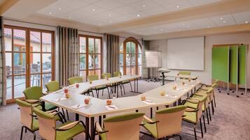 A conference room with a long table, chairs, a projector, and a whiteboard.