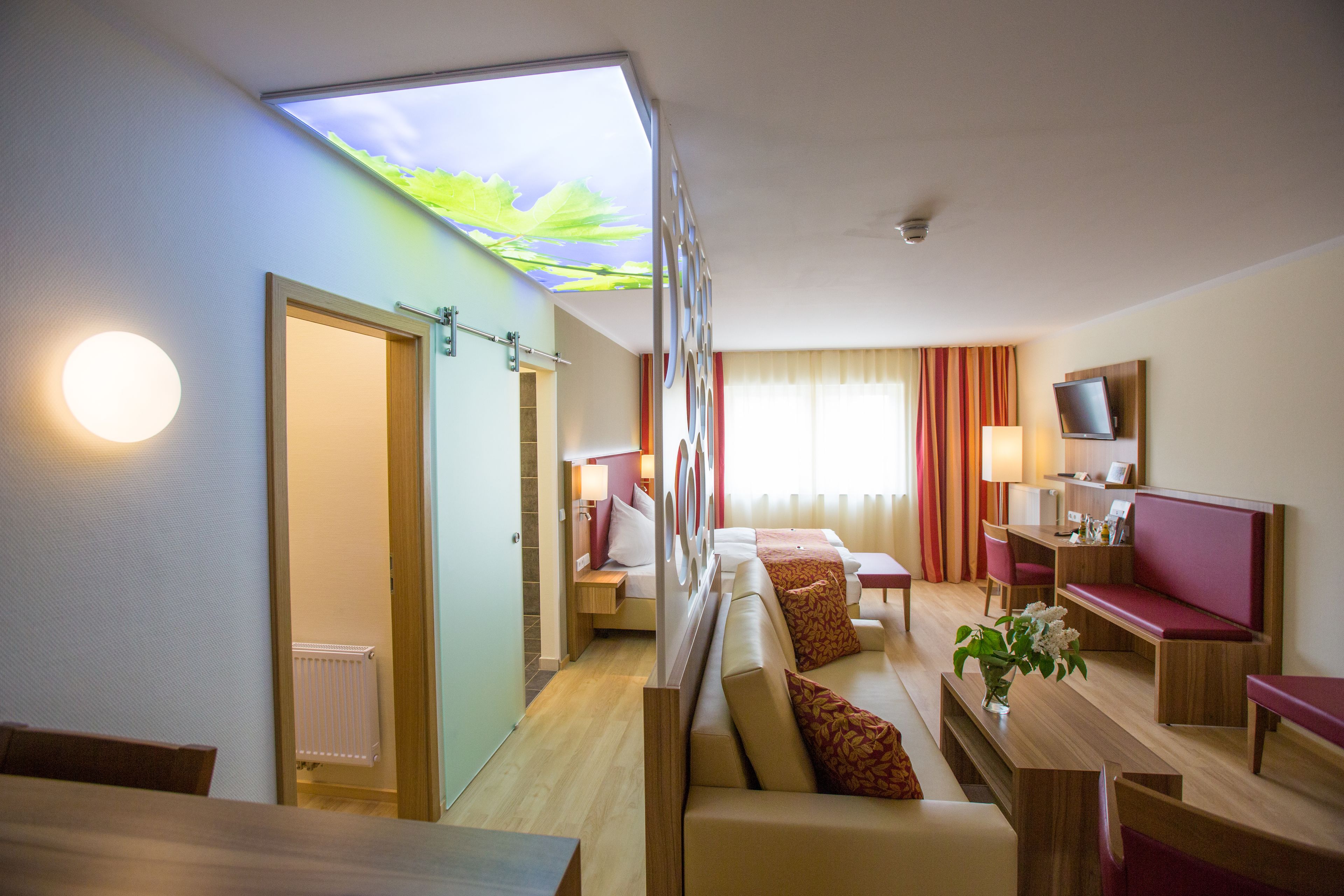 A hotel room with a bed, seating area, and a TV.