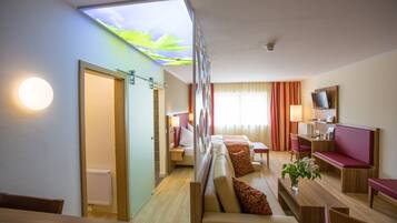 A hotel room with a bed, seating area, and a TV.