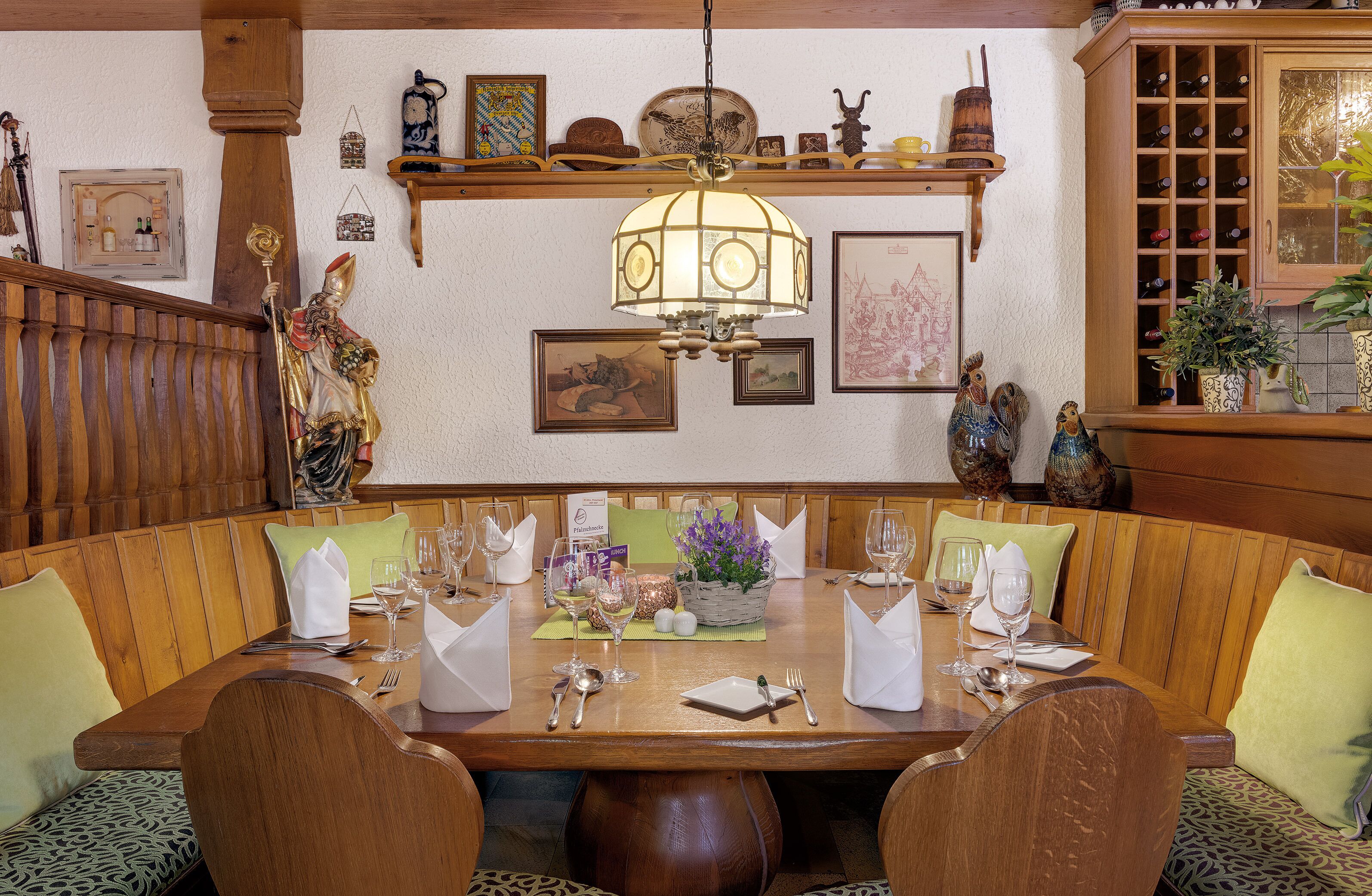 A dining area with a wooden table set for a meal, surrounded by cushioned benches.