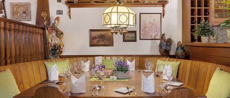 A dining area with a wooden table set for a meal, surrounded by cushioned benches.