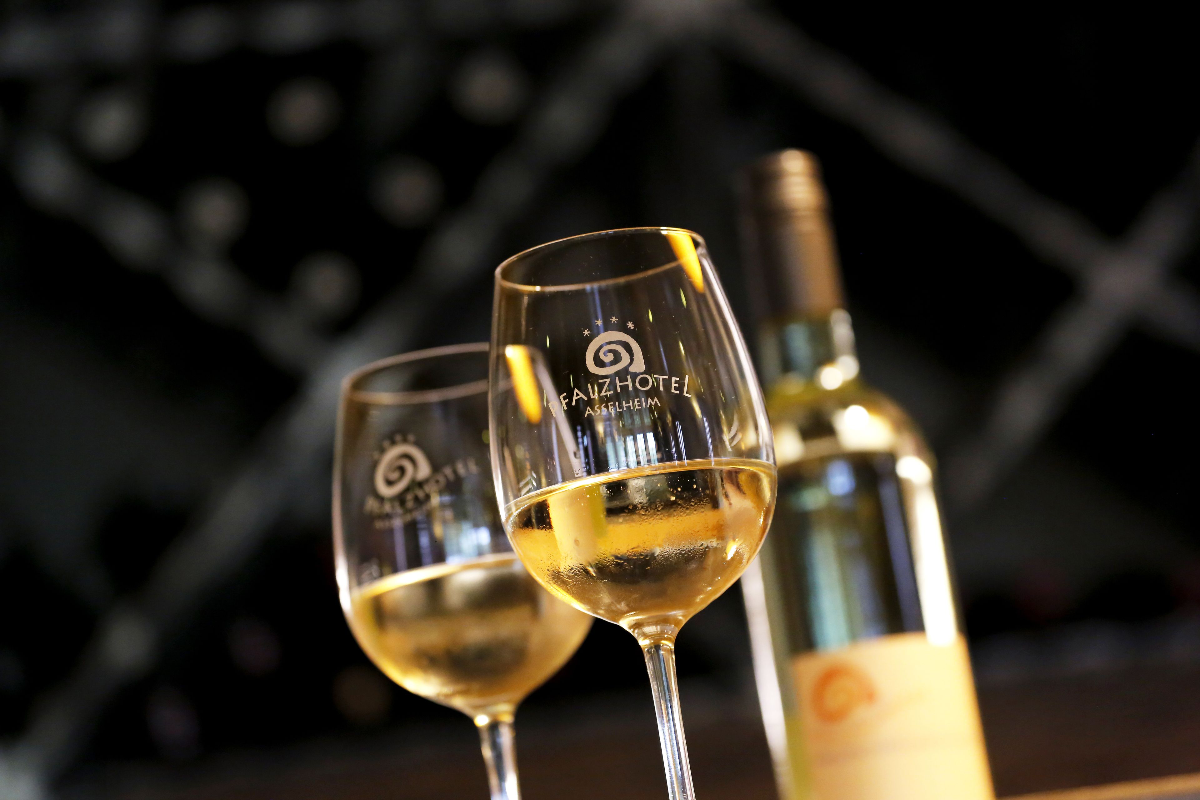 Dos copas de vino con una botella al fondo.