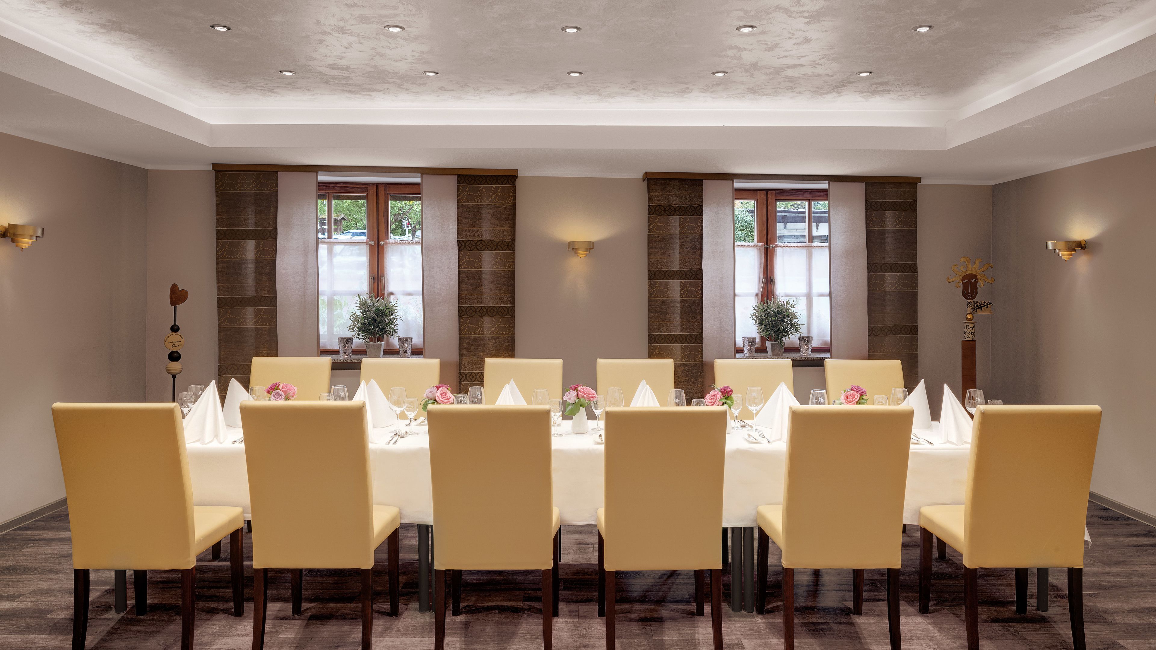 A conference room with a long table, six chairs, and two windows with curtains.